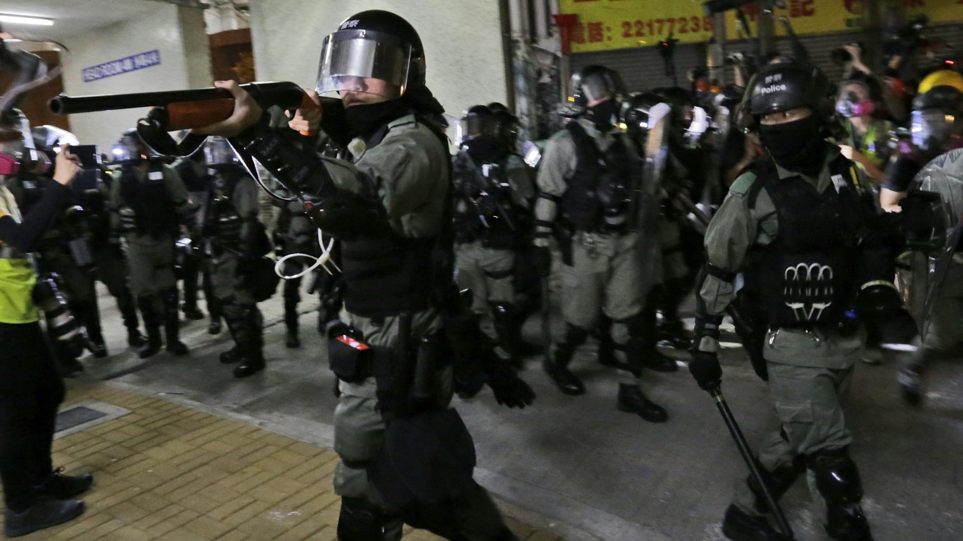 Polizisten richten ihre Waffen während eines Zusammenstoßes auf Demonstranten.