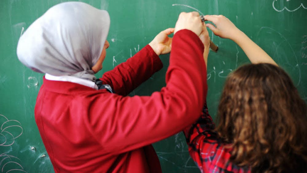 Eine Lehrerin mit Kopftuch unterrichtet.