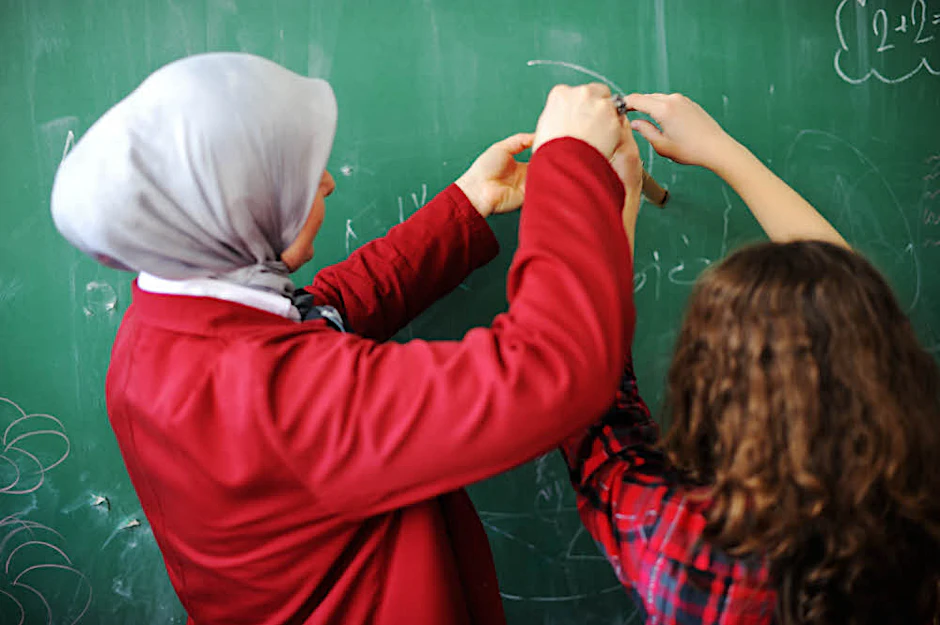 Eine Lehrerin mit Kopftuch unterrichtet.