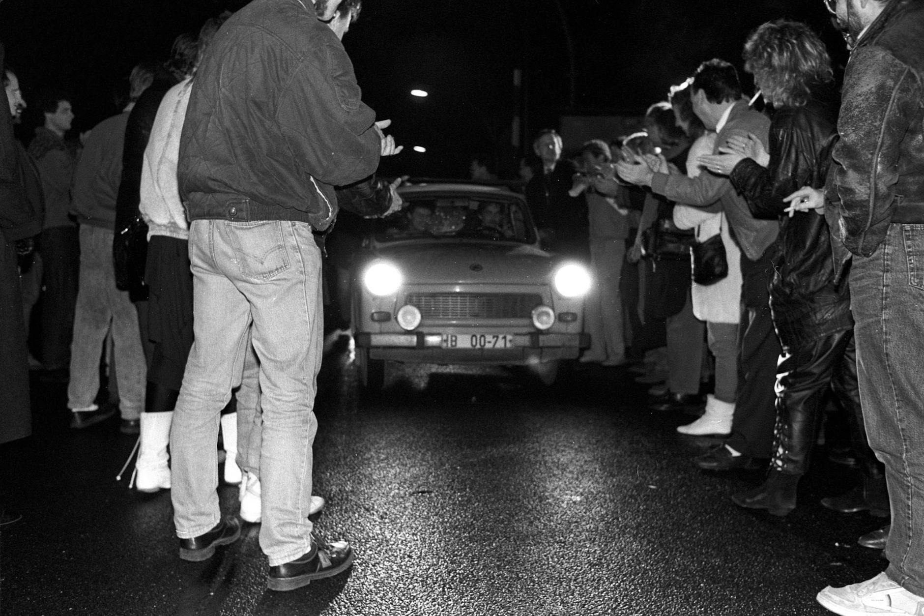 9. November 1989: Trabis werden von einer begeisterten Menge an einem Grenzübergang in Berlin empfangen.