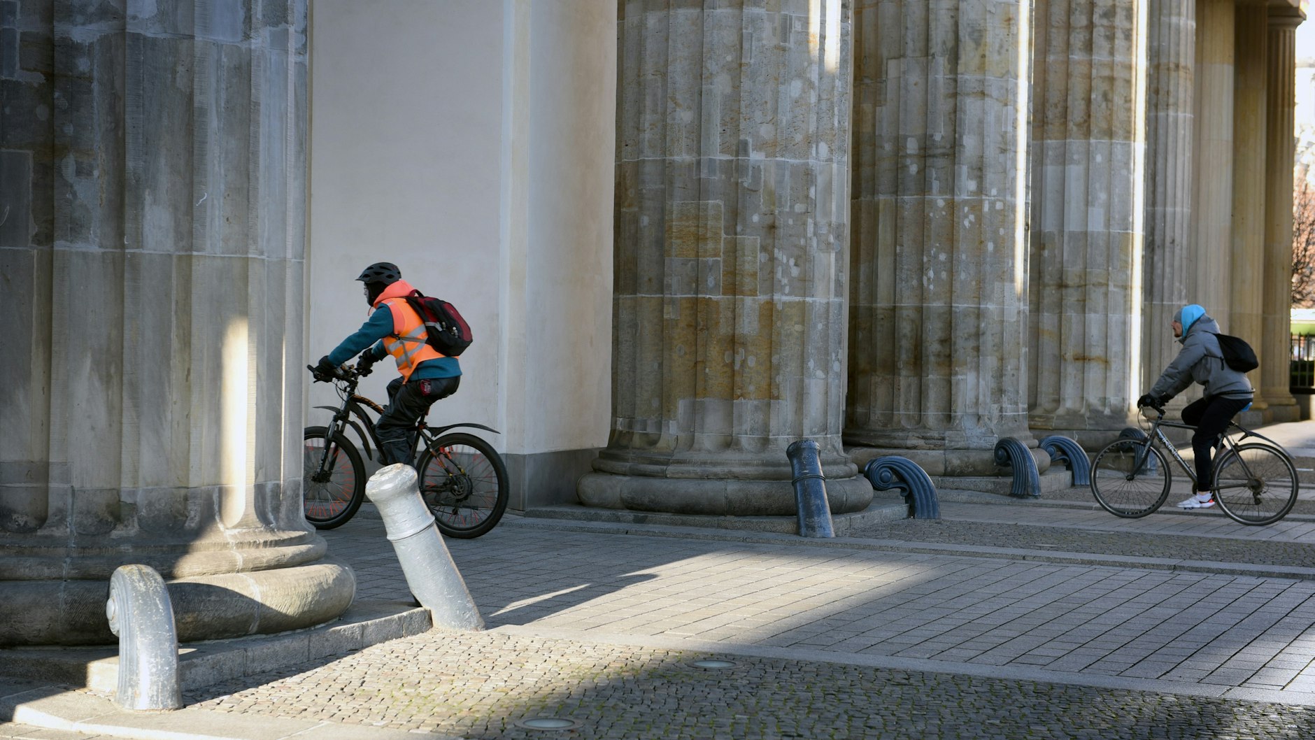 Zwei Radfahrer  durchqueren das Brandenburger Tor. Nicht immer sind an dem Berliner Wahrzeichen so wenige Fußgänger unterwegs.