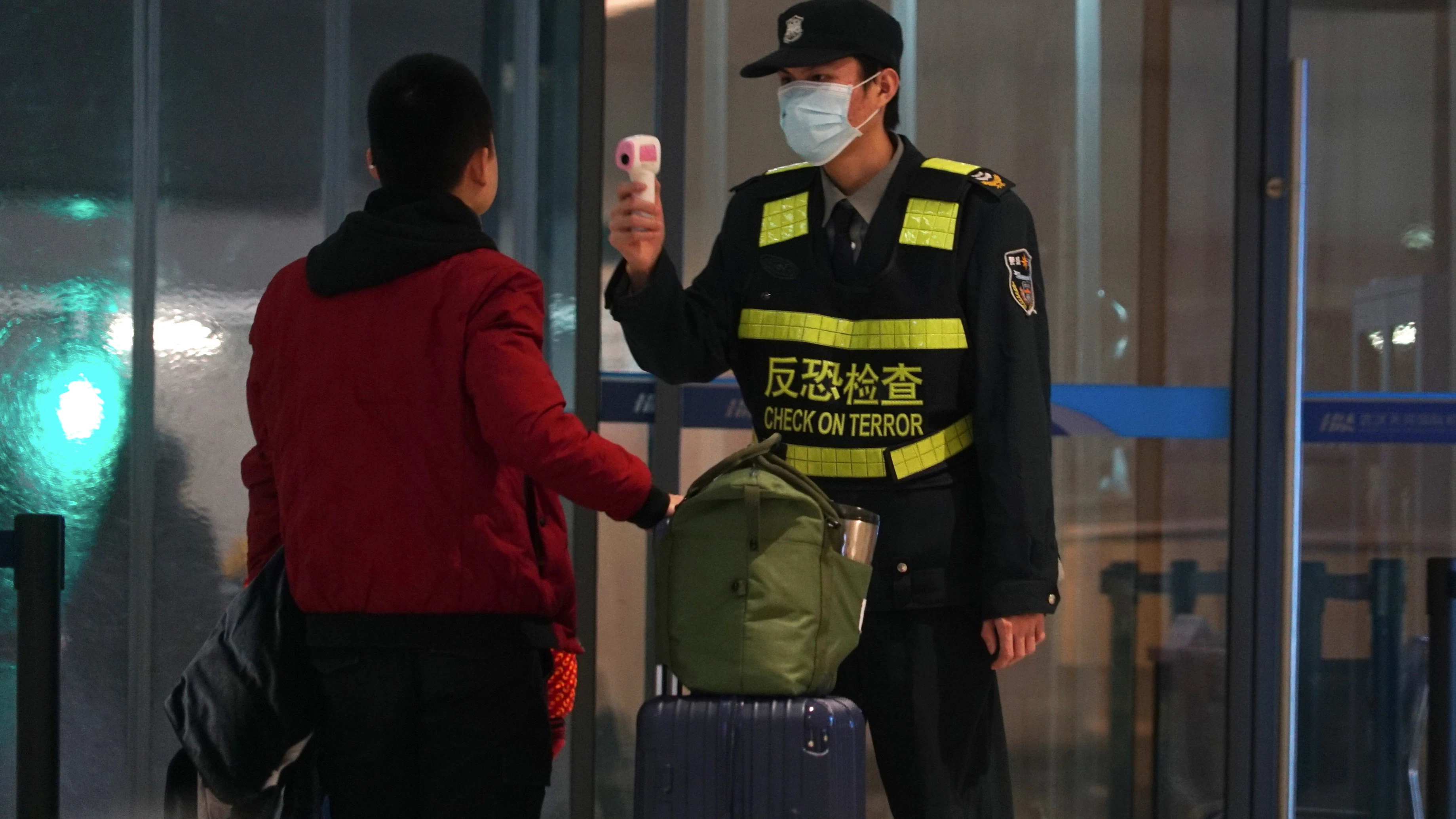Schutzmaßnahme: Ein Mitarbeiter des Flughafens Wuhan Tianhe International misst bei einem Reisenden die Temperatur.
