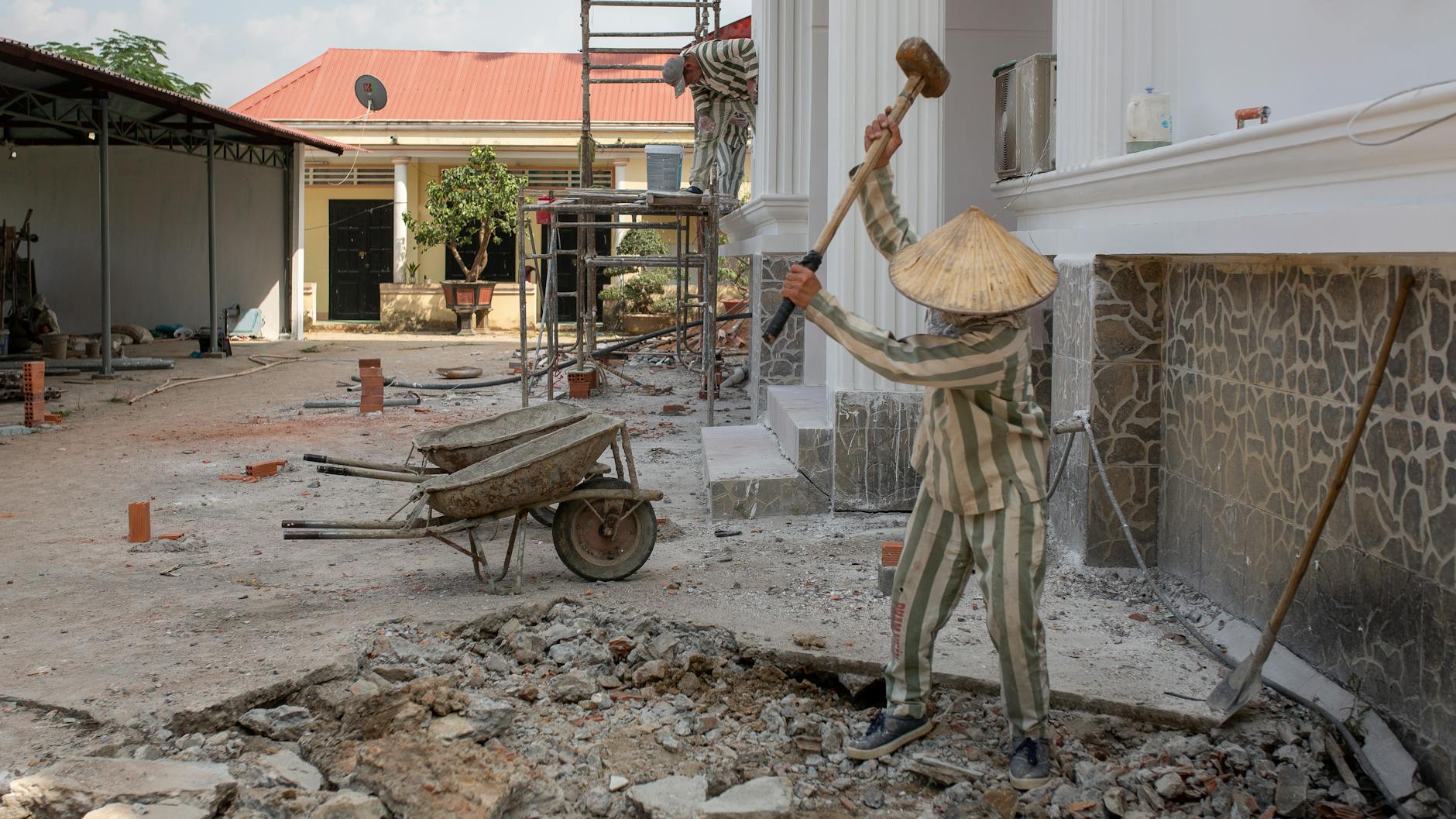 Ein Insasse des Thu-Duc-Gefängnisses zerschlägt mit einem großen Hammer Beton im Gefängnishof. Häftlinge in Vietnam müssen tagsüber schwere Arbeit auf dem Gefängnisgelände verrichten.