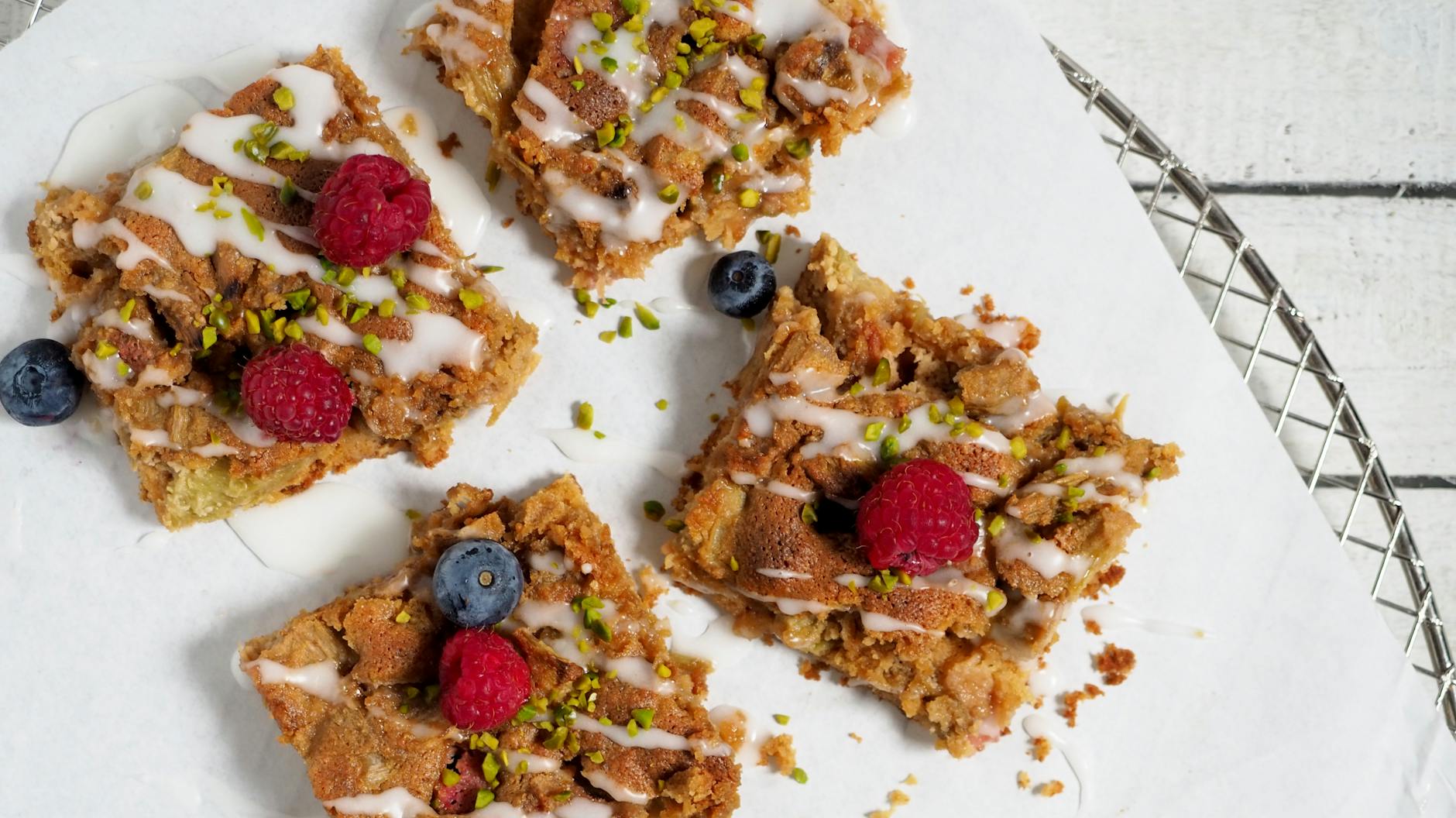 Rhabarberkuchen vom Blech mit gehackten Pistazien, hier garniert mit frischen Beeren.