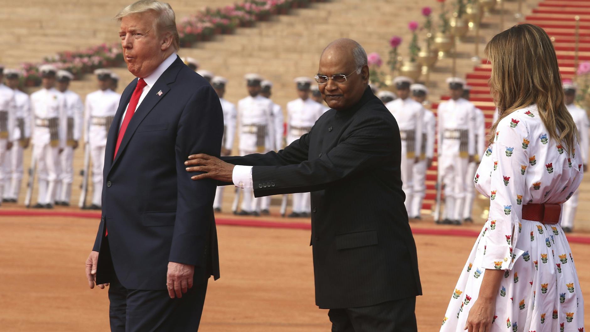 Donald Trump (l.) wird von Ram Nath Kovind (m.), Präsident von Indien, positioniert. Melania Trump beobachtet die Szene.