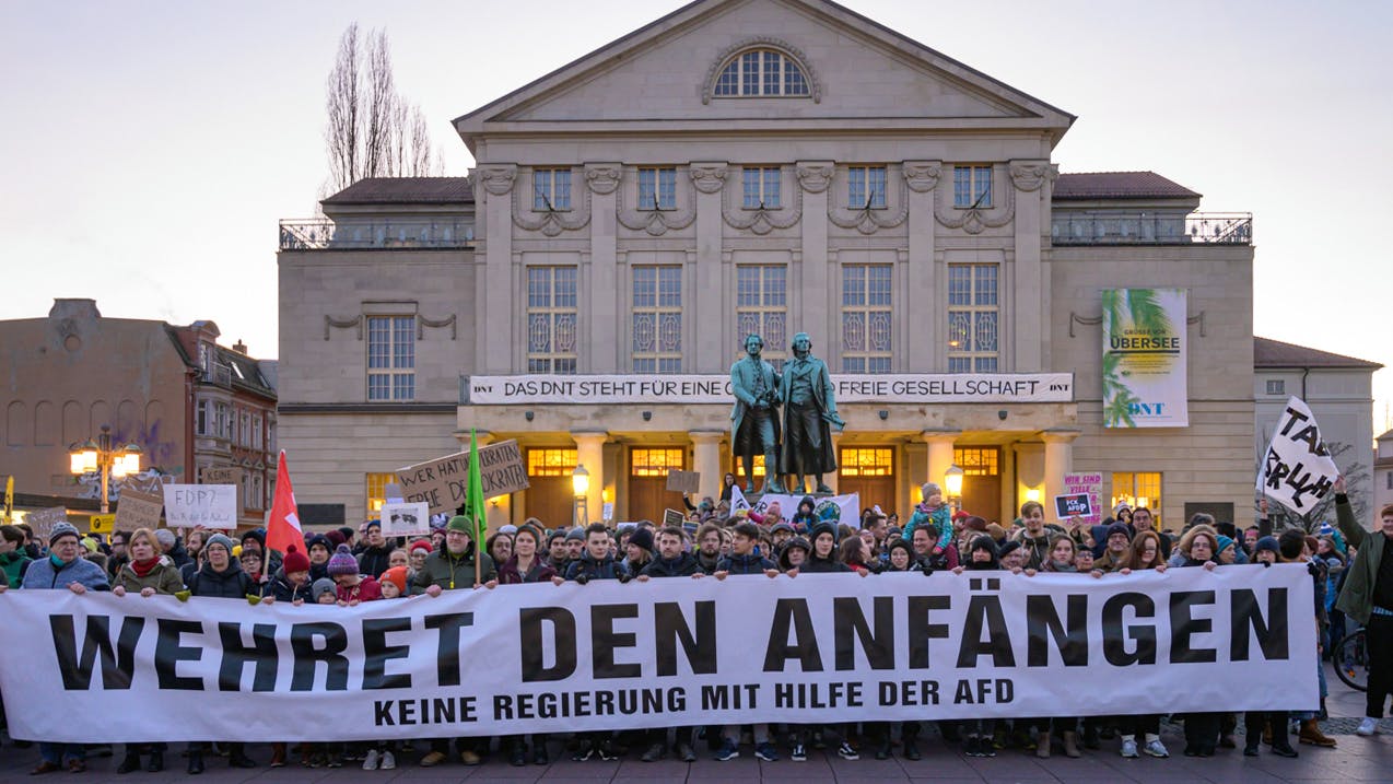 „Wehret den Anfängen - Keine Regierung mit Hilfe der AFD“ steht auf einem Transparent, das Demonstranten vor dem Theater und dem Goethe- und Schillerdenkmal halten. Die Menschen demonstrieren gegen den neuen Ministerpräsidenten von Thüringen.