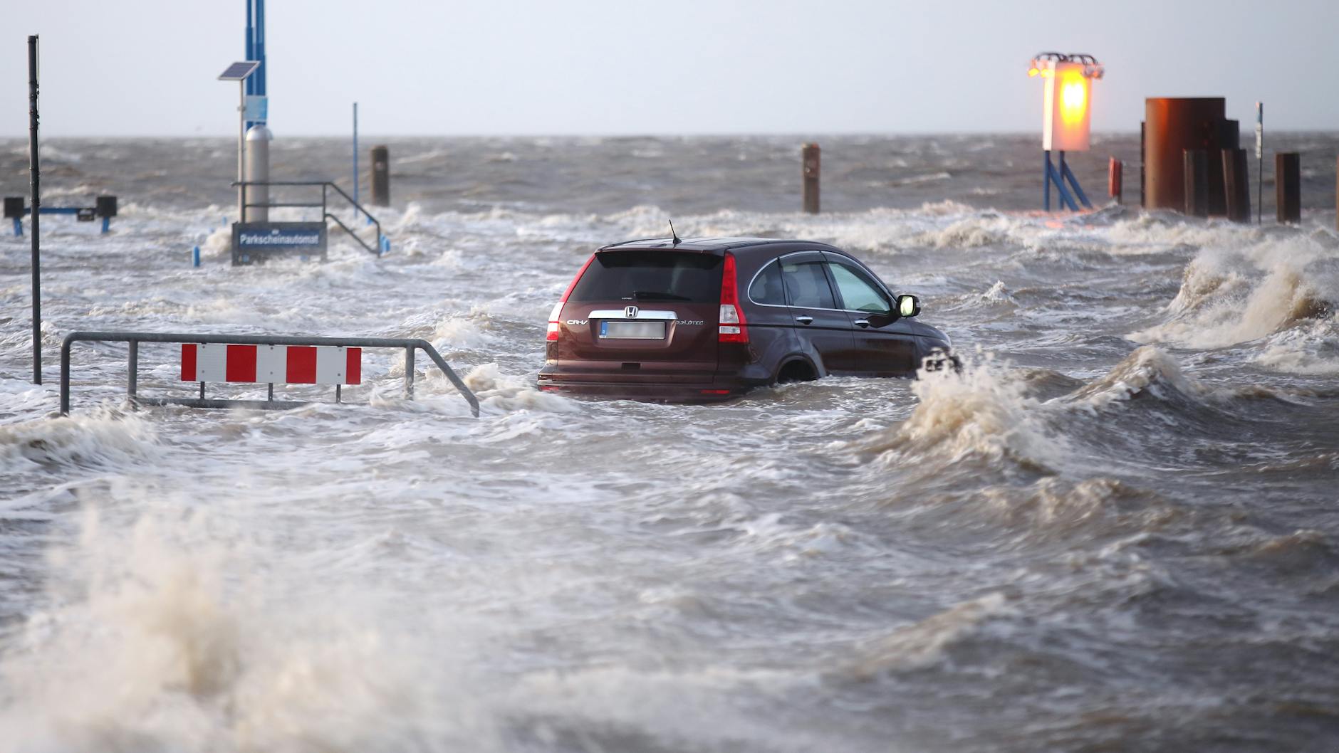 Das vom Atlantik kommende Orkantief „Sabine“ rückt näher. Ein Auto steht auf einem Parkplatz der Mole des Fähranlegers am Hafen von Dagebüll im Wasser der Nordsee.