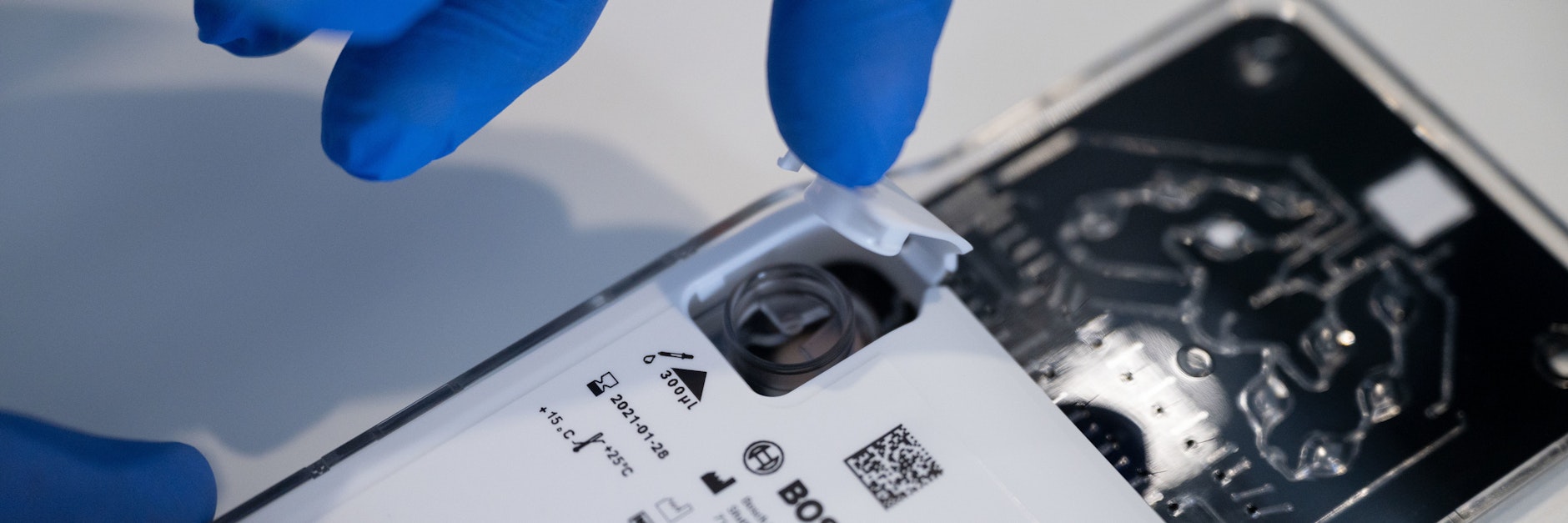 Ein Medizinisch-Technischer Assistent schließt eine mit einer Testflüssigkeit gefüllte Kartusche für ein Analysegerät.