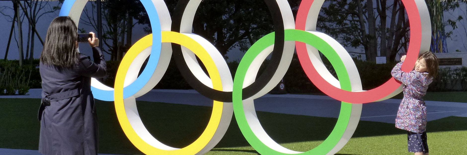 Ein Bild aus besseren Tagen. Eine kleine Japanerin posiert für ihre Mutter vor den olympischen Ringen. 