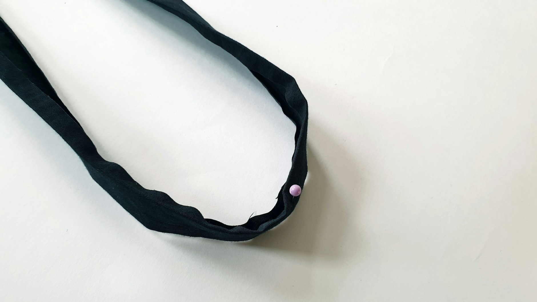 Das Schrägband teilt man in zwei 75cm lange Stücke und markiert sich beim ersten Stück die Mitte davon mit einer Stecknadel.