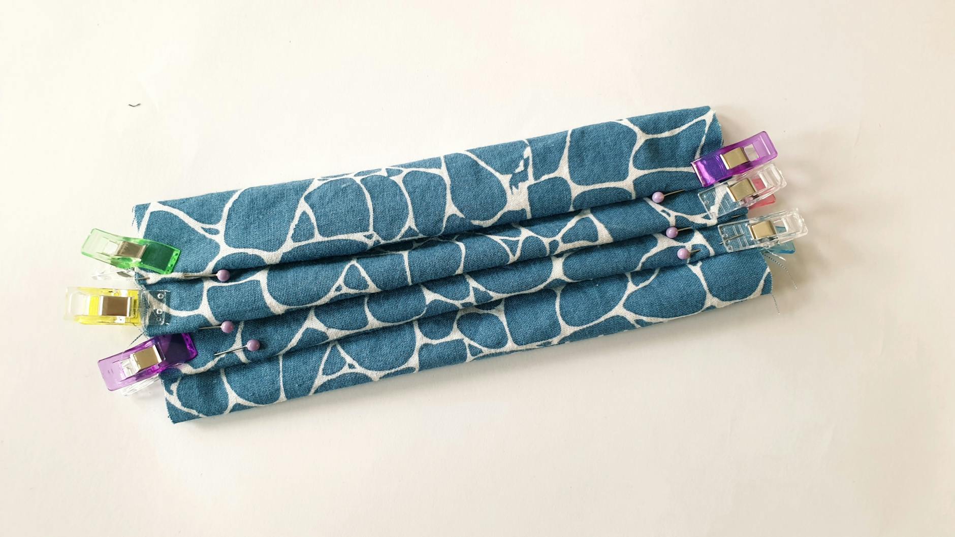 So faltet man auch die anderen beiden Falten: an den orangefarbenen Nadeln nach unten, an den lilafarbenen nach oben.