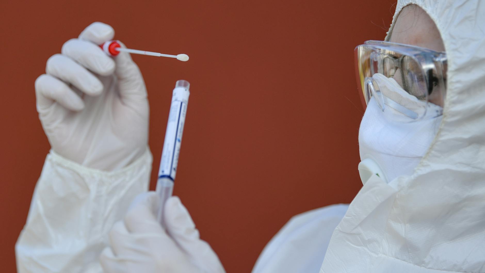 Eine Arzthelferin in Schutzausrüstung hält einen Abstrichtest auf das Coronavirus Sars-Cov-2 in ihren Händen.