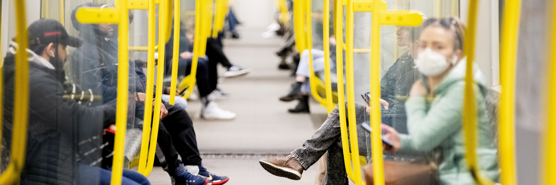 Fahrgäste sitzen in einer U-Bahn, wobei eine Frau einen Mundschutz trägt.&nbsp;