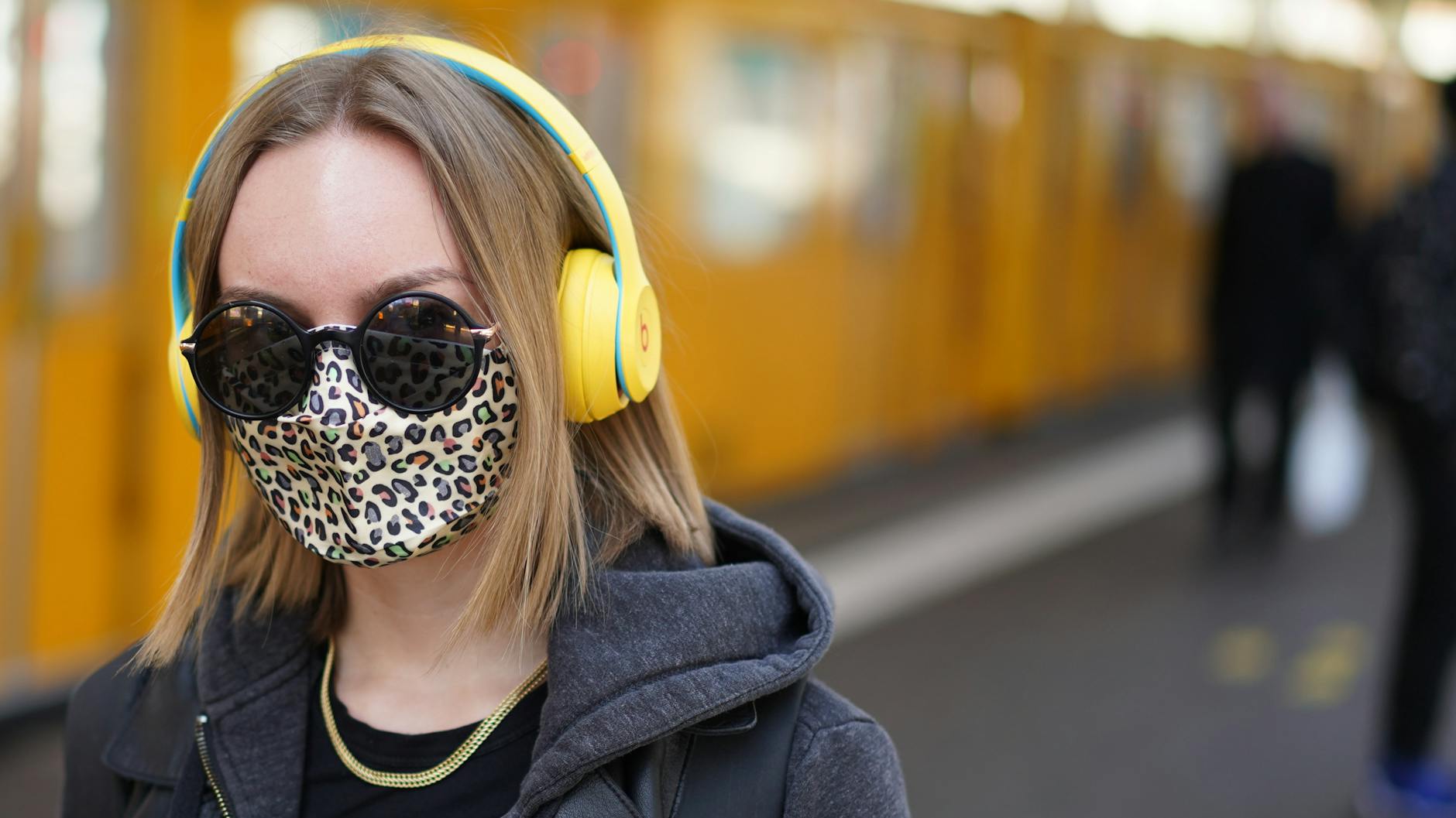 Junge Frau mit Mundschutz am Kottbusser Tor vor einem Zug der U-Bahnlinie U1. 