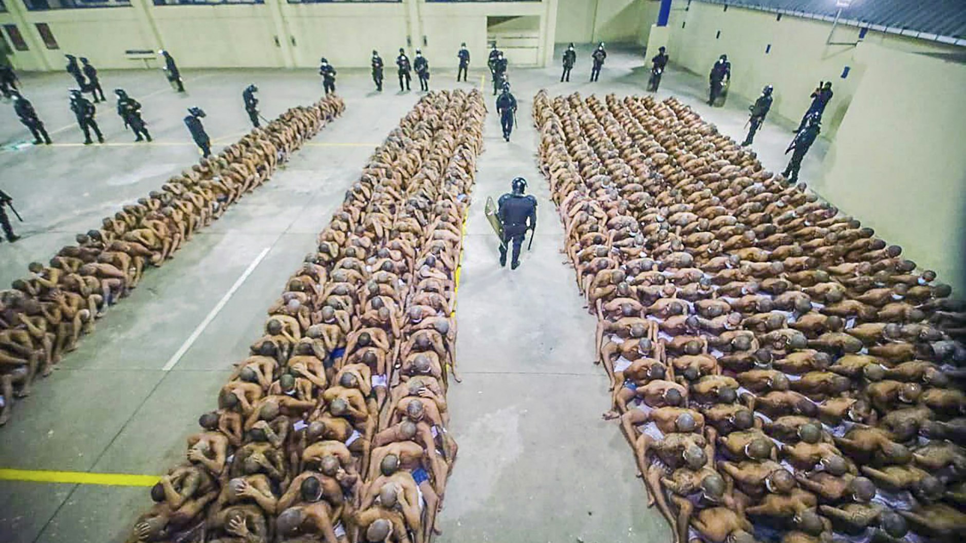 Zwischen den Häftlingen patrouillieren schwer bewaffnete Wachleute.