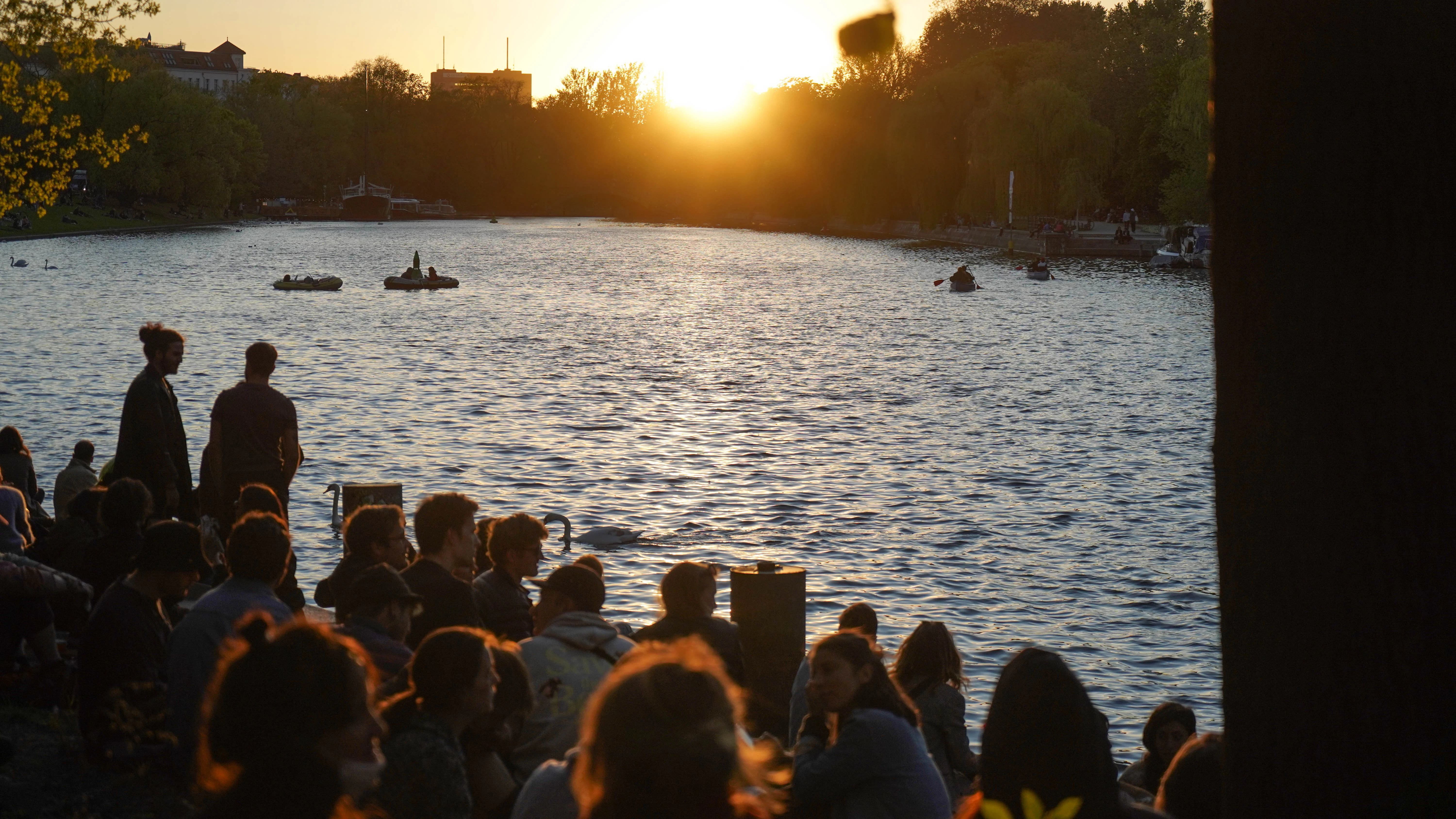 Zahlreiche Menschen genießen den Sonnenuntergang am Ufer des Landwehrkanals.