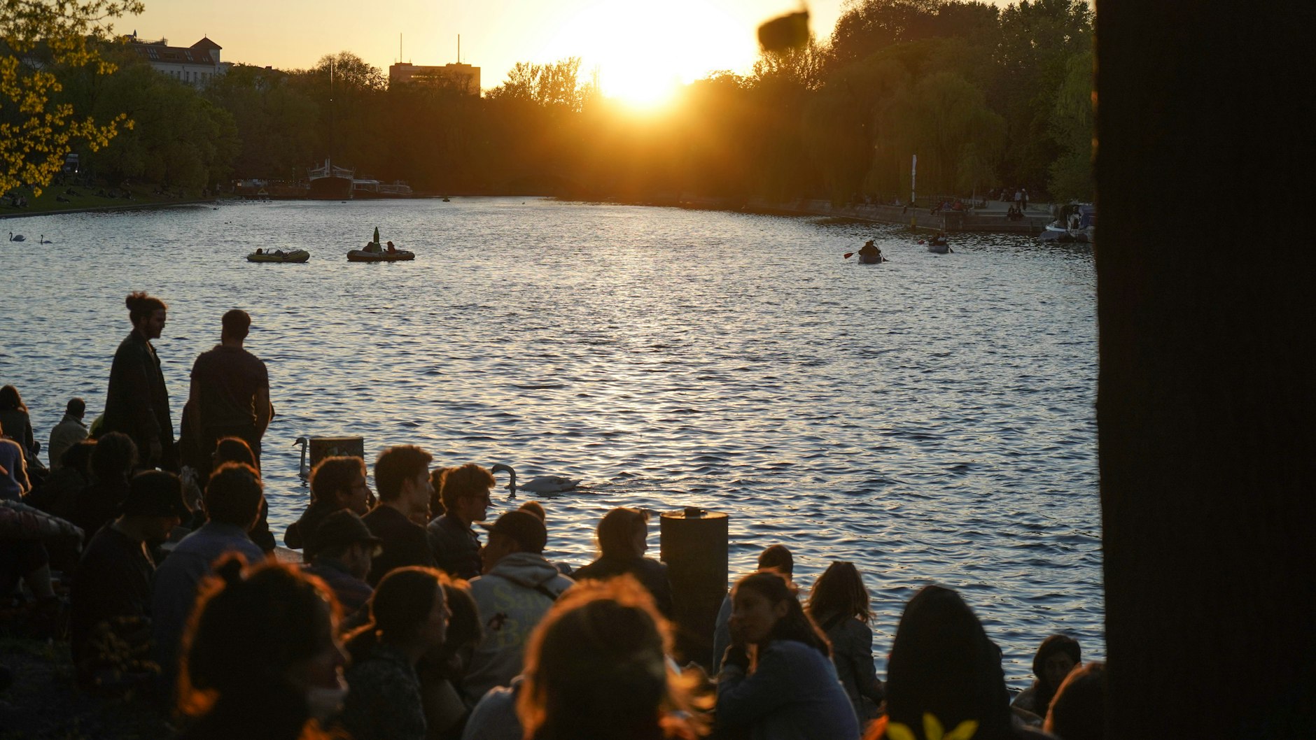 Zahlreiche Menschen genießen den Sonnenuntergang am Ufer des Landwehrkanals.