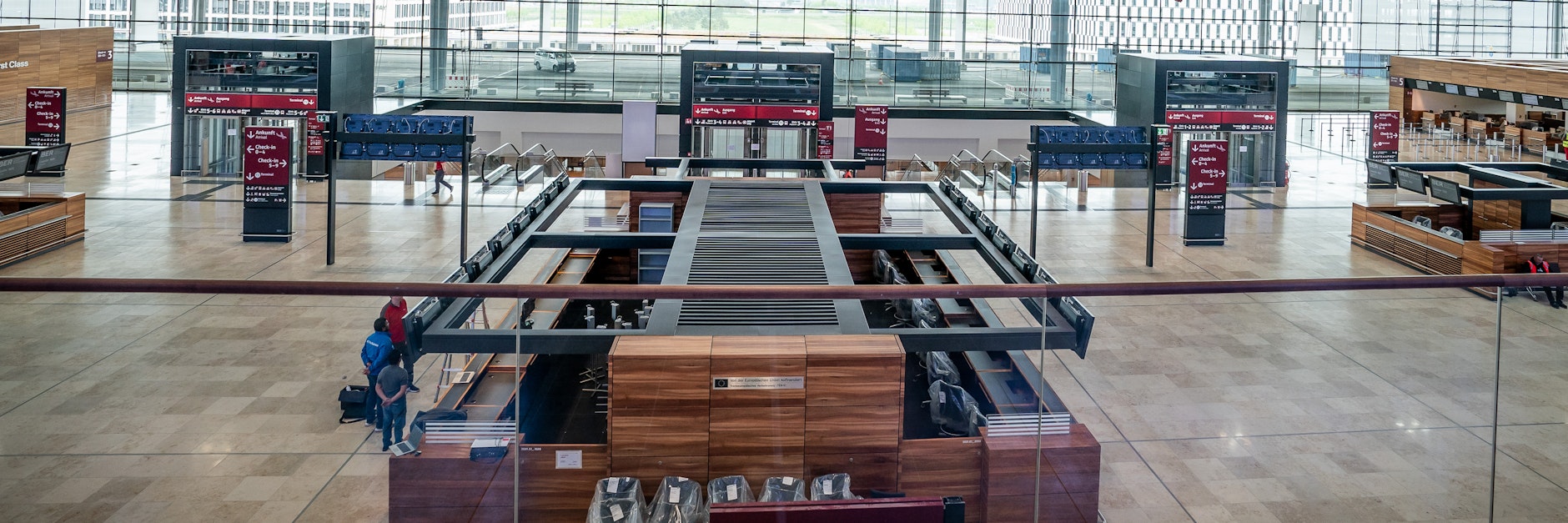 Wenige Techniker werkeln in der ansonsten menschenleeren Abflughalle des neuen Flughafens Berlin-Brandenburg Willy-Brandt.