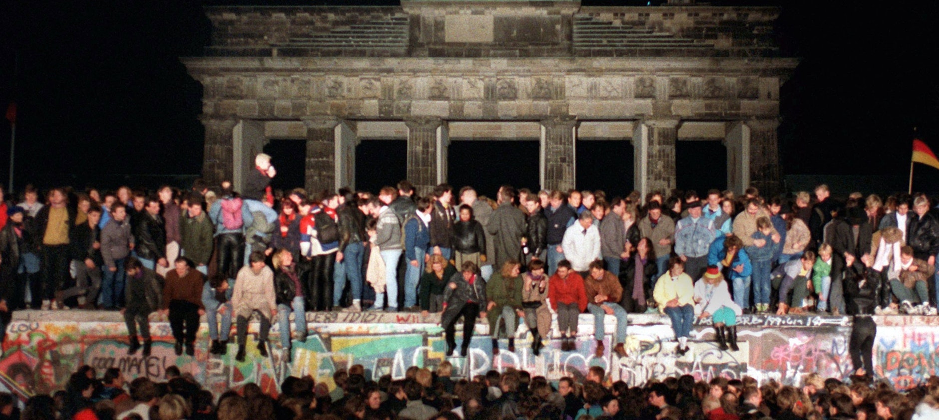 Jubelnde Menschen erklimmen am 10.11.1989 die Berliner Mauer vor dem Brandenburger Tor.