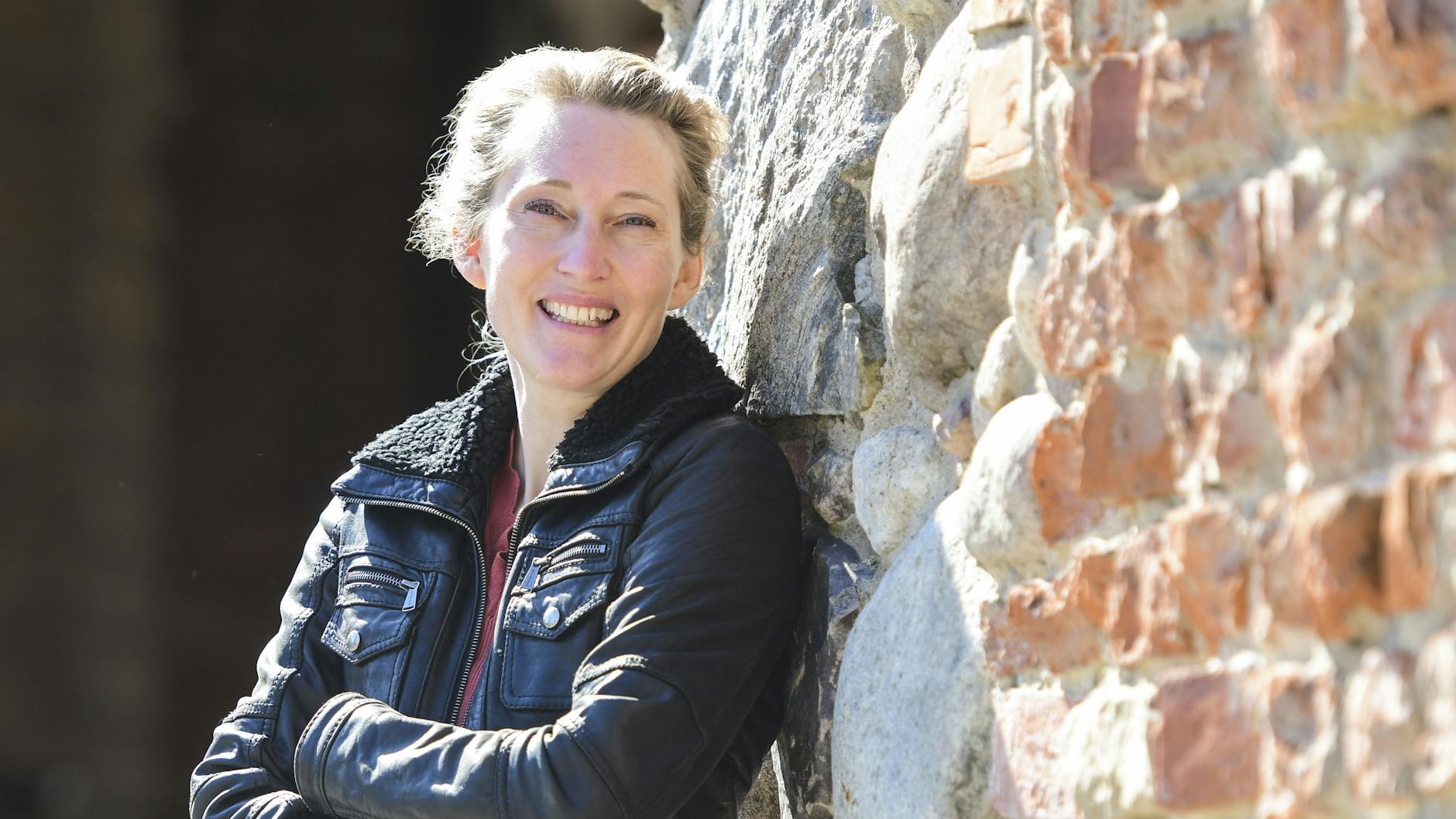 Dr. Urte Evert lehnt am Backstein-Mauerwerk der Zitadelle: Hier hat sie ihren Arbeitsplatz. Die Festung ist auch ihr Lieblingsort in Spandau.