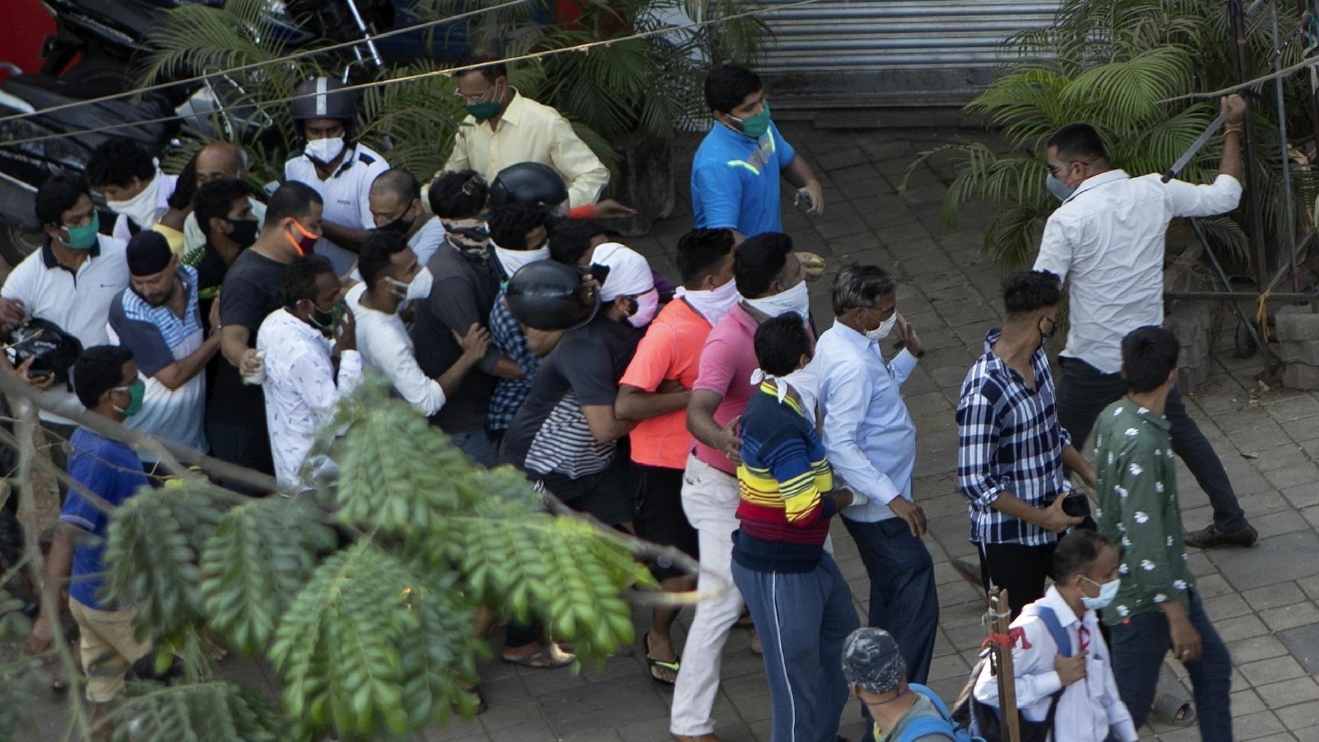 Mumbai: Ein Polizist in Zivil holt mit einem Schlagstock gegen die in einer Warteschlange stehenden Kunden eines Alkoholika-Ladens aus. Sie haben nicht den nötigen Abstand zueinander eingehalten, sagte der Beamte.