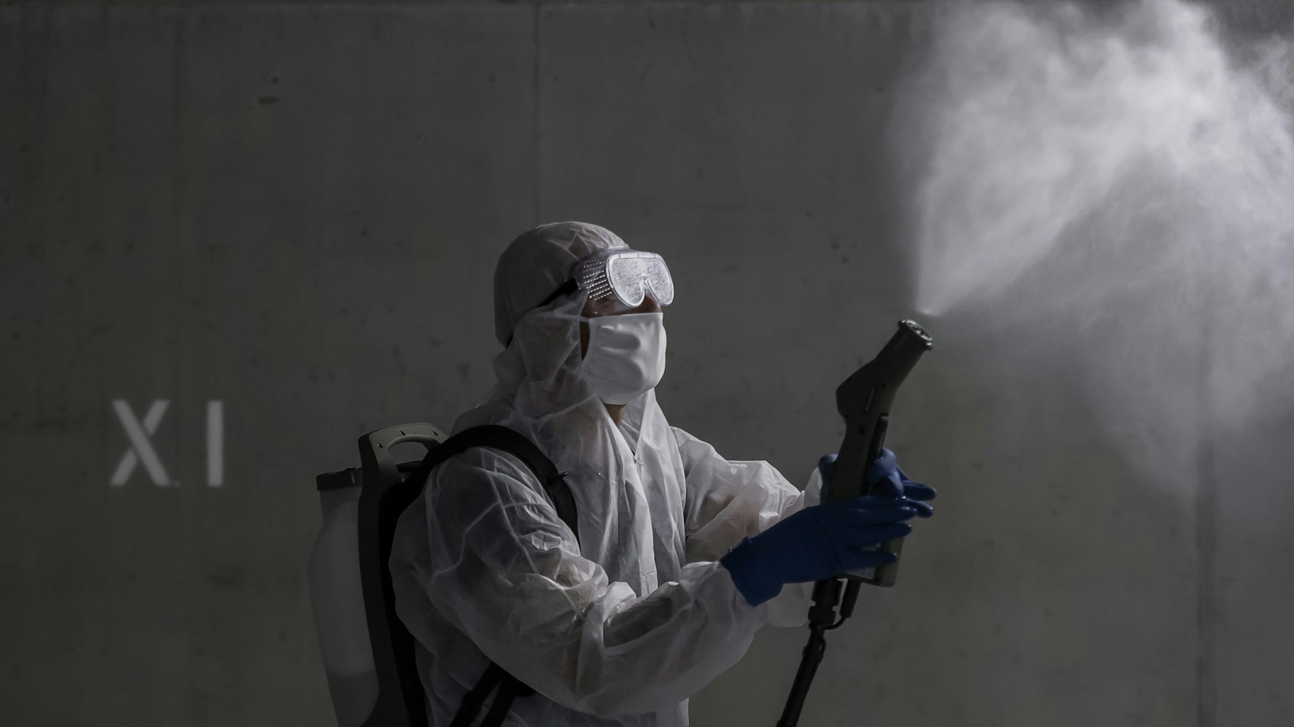 Ein Mann in Schutzkleidung desinfiziert die Garage eines Mehrfamilienhauses.