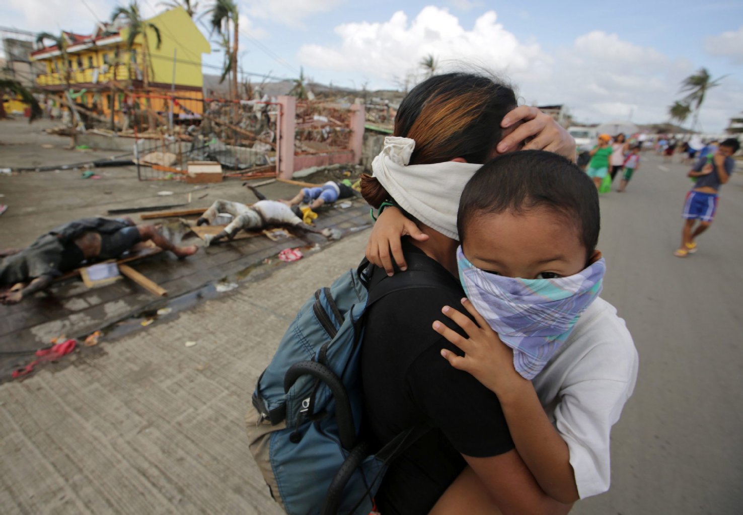 Die Straßen von Tacloban sind mit Leichen gesäumt. Gegen den Verwesungsgeruch versucht eine Mutter sich und ihr Kind mit Tüchern vor Mund und Nase zu schützen.