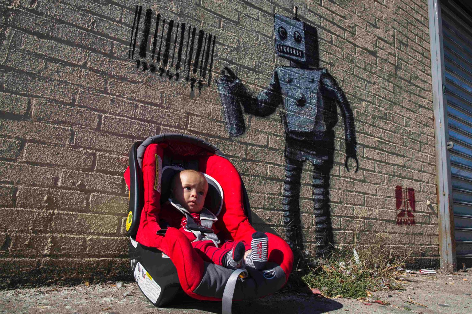 So jung und schon ein Banksy-Model: Der siebenmonatige Benjamin Butler wird von seiner Mutter neben einem Banksy-Graffito auf Coney Island fotografiert.