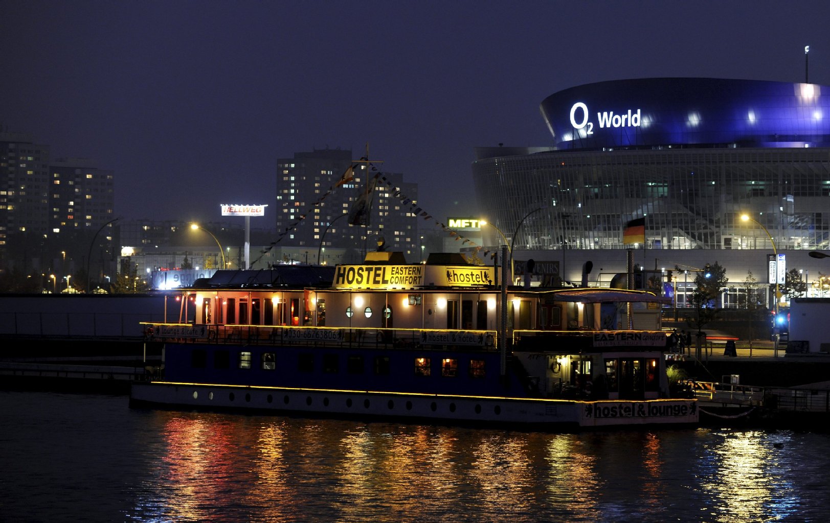 Weniger schön, aber genauso bekannt ist die 02-World-Arena in Friedrichshain. Im Vordergrund liegt das einzige Hostel-Schiff Berlins. Das Schiff ist besonders bei jugendlichen Rucksackreisenden beliebt.