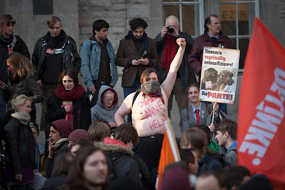 Ein Gegendemonstrant hat sich die Aufschrift "Danke Anne Helm" auf den nackten Oberkörper geschrieben.