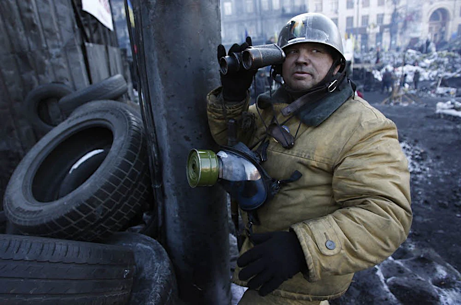 Ein Demonstrant mit Helm, Gasmaske und Fernglas auf dem Maidan in Kiew.