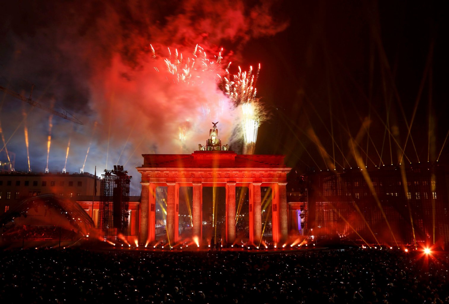Feuerwerk und Strahler tauchen das Brandenburger Tor in rotes Licht.