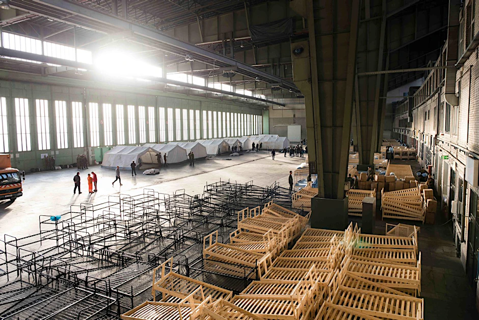 Doppelstockbetten aus Metall und Holz stehen in einem Hangar des ehemaligen Flughafen Tempelhof.