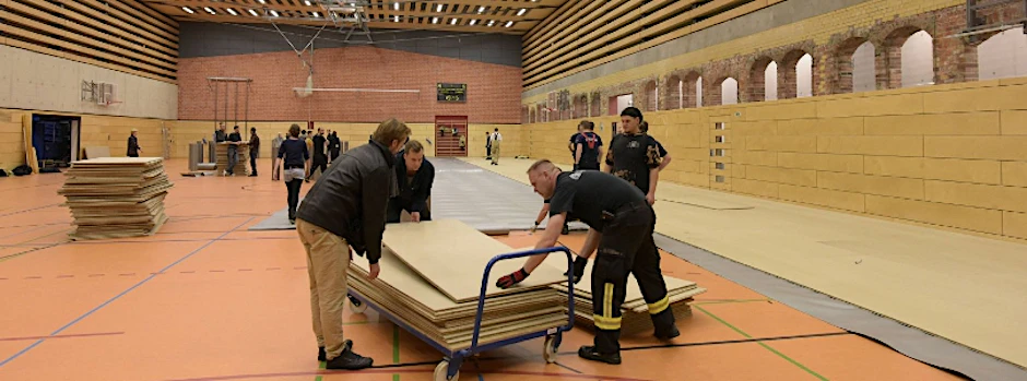 Feuerwehrleute und zivile Helfer errichten in einer Turnhalle in der Hausburgstraße in Friedrichshain eine Notunterkunft für Flüchtlinge.