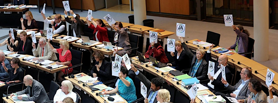 Abgeordnete der Grünen (r) und der Linken halten am 11.06.2015 während der Sitzung des Berliner Abgeordnetenhauses in Berlin, Zettel mit einem JA zur Ehe für Alle hoch.