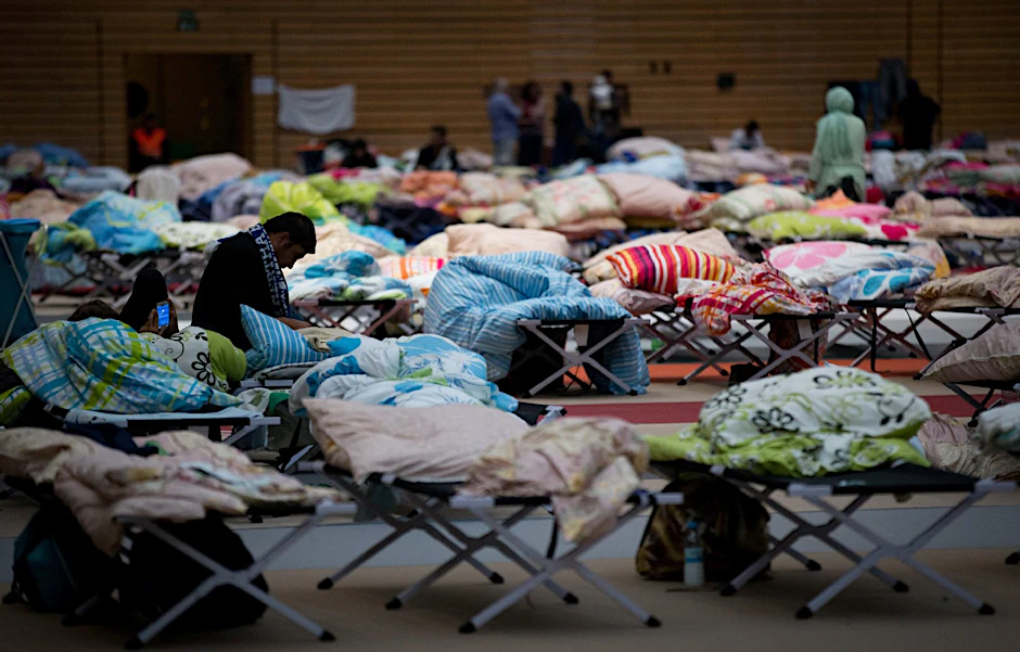Flüchtlinge sitzen in Berlin in einer großen Sporthalle am Olympiapark im Stadtteil Charlottenburg.