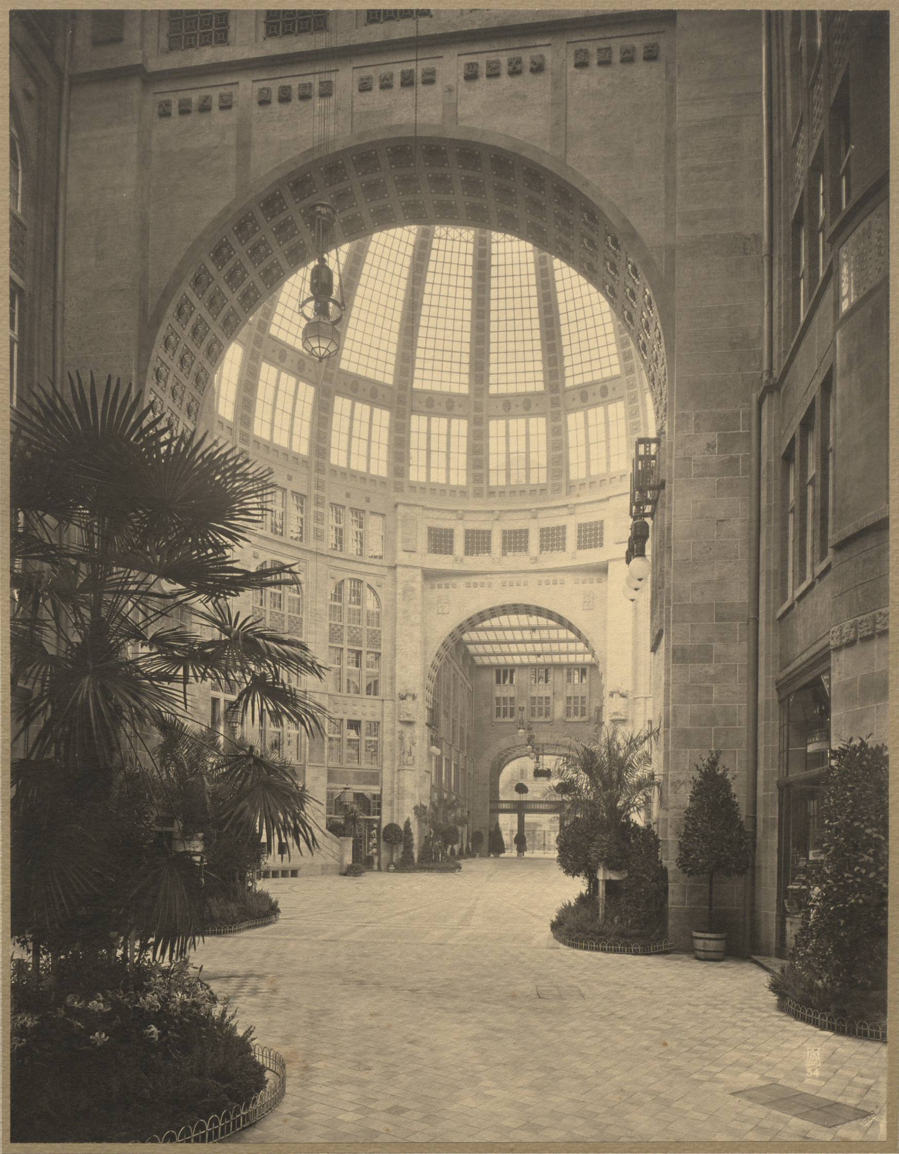 Blick in den zentralen Kuppelsaal und zum Ausgang Richtung Friedrichstraße. Die Ausstattung ist edel, Palmen verbreiten ein exotisches Flair.