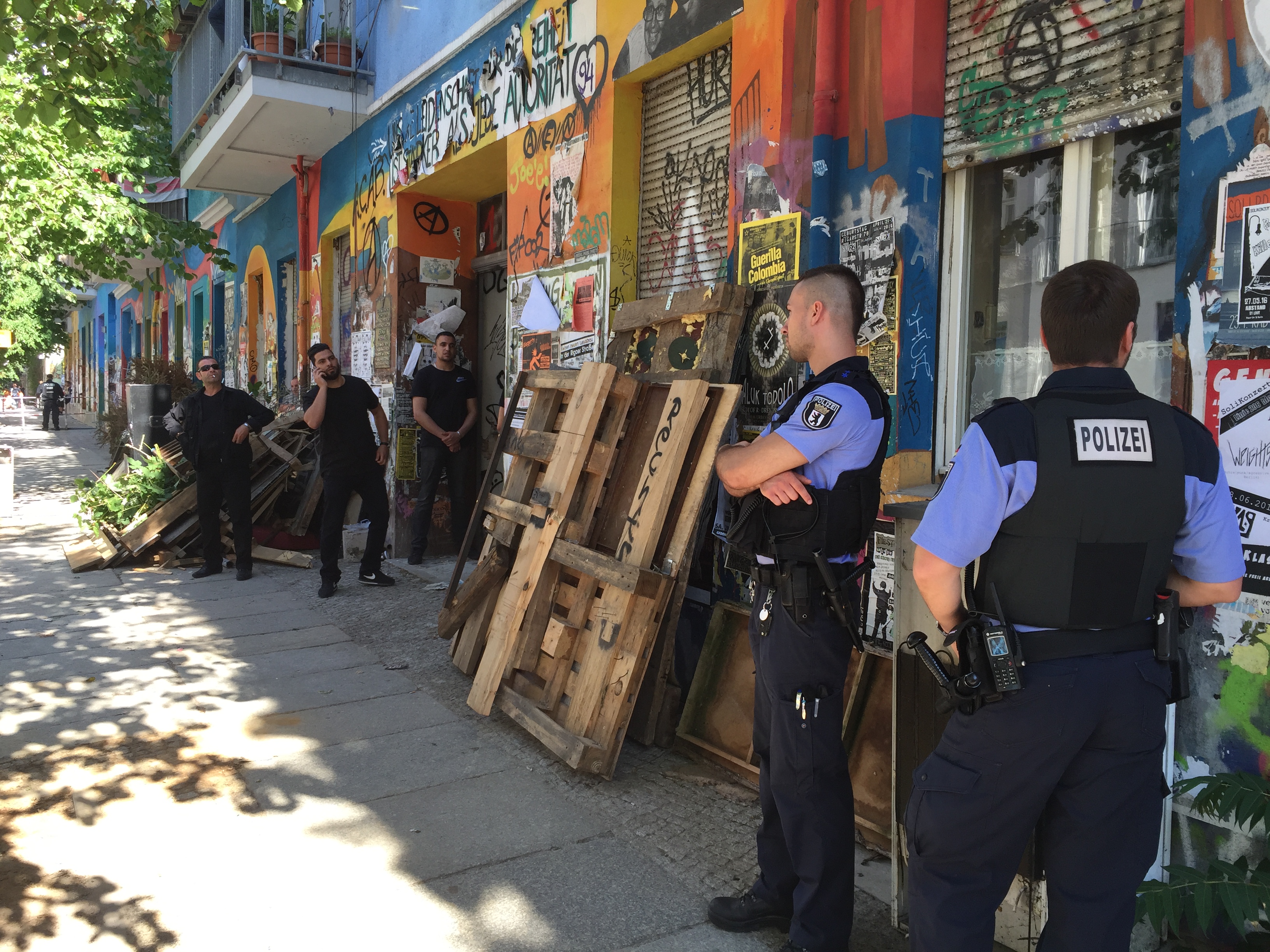 Polizeibeamte stehen bei der Räumung eines Gebäudeteils in der Rigaer Straße 94 in Friedrichshain vor dem Hauseingang.