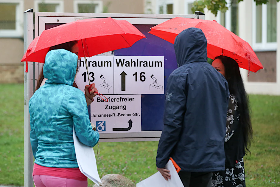 Wahlhelfer mit Regenschirmen in Mecklenburg-Vorpommern.