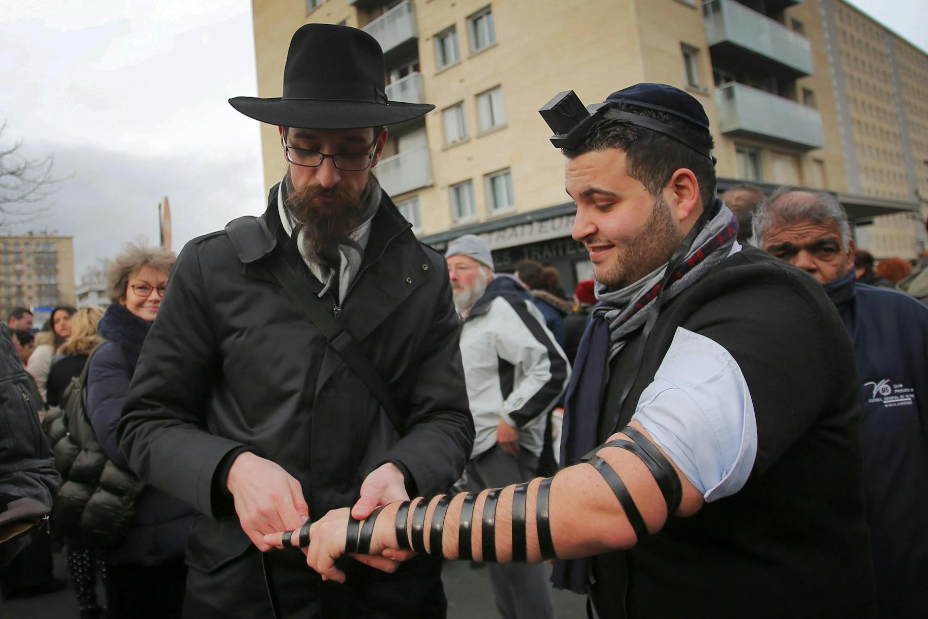 Zwei orthodoxe Juden bereiten sich mit dem Anlegen eines jüdischen Gebetsriemens (Tefillin) auf ein Gebet vor.
