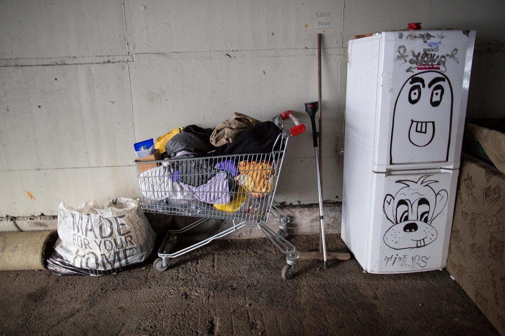 Ob er wohl funktioniert? Ein Kühlschrank steht unter einer Brücke, unter der Obdachlose leben. Als eine Art Regal dient ein Einkaufswagen, in dem ein Wohnungsloser sein Hab und Gut gesammelt hat.