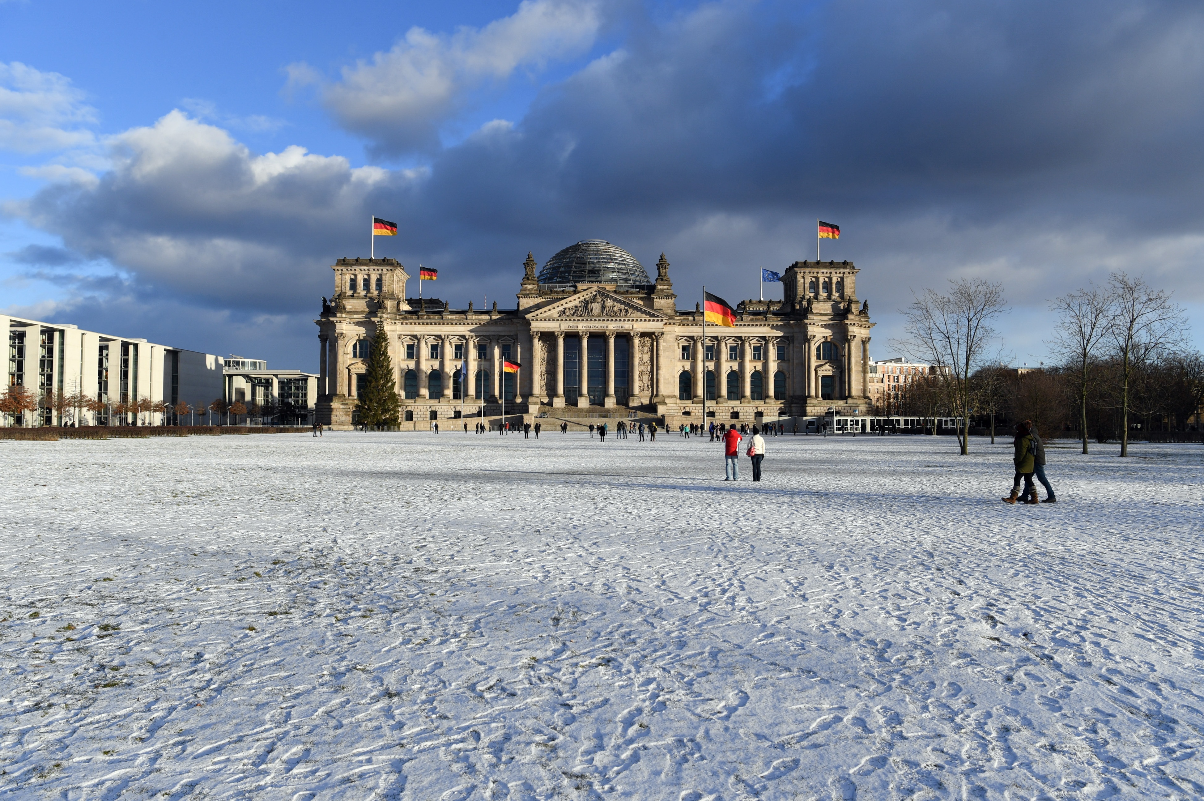 Schnee liegt in Berlin auf der Wiese vor dem Reichstag.