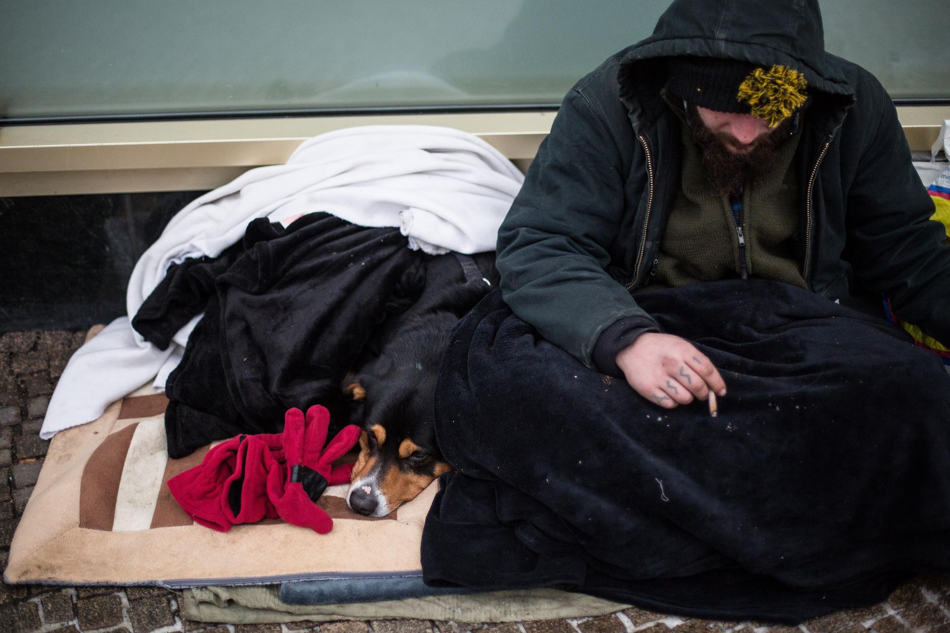 "Baum", wie sich dieser Obdachlose nennt, sitzt mit seinem Hund in der Nähe des Alexanderplatzes. Auf seiner Hand steht das Tattoo "Assi".
