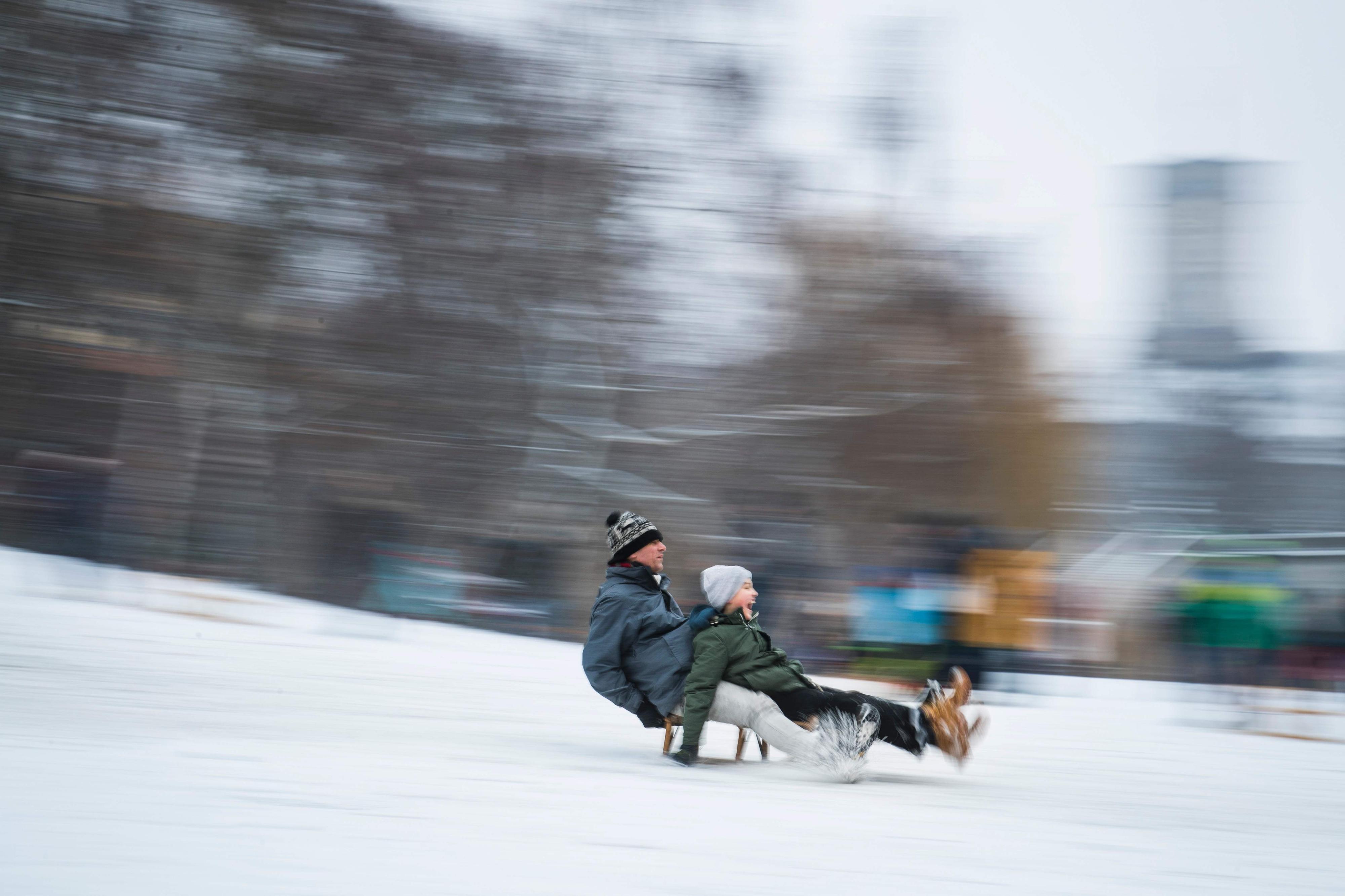 Kinder und Erwachsene rodeln mit dem Schlitten im Schnee.