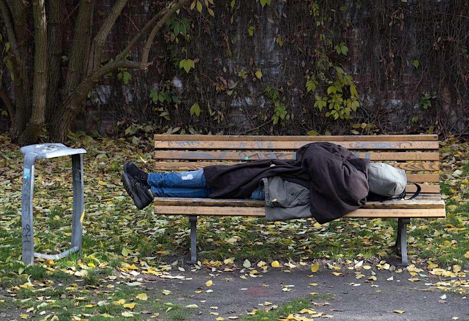 Ein Obdachloser schläft in Berlin auf einer Parkbank. 