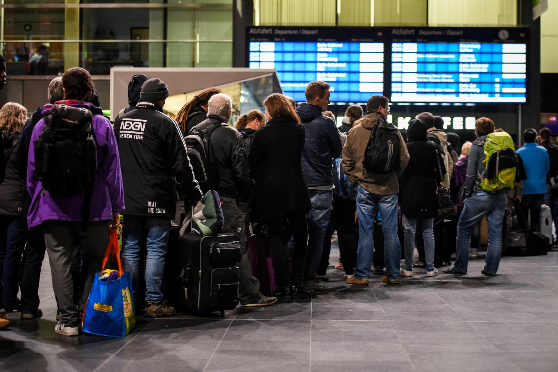 Fahrgäste stehen auf dem Hauptbahnhof in Berlin in einer Warteschlange an einem Informationsschalter der Deutschen Bahn an.