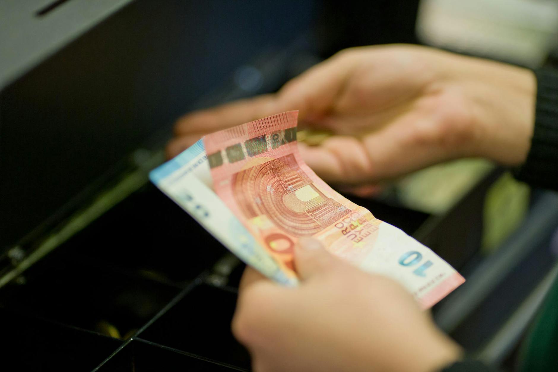 Eine Kassiererin an einer Supermarktkasse zählt das Wechselgeld.