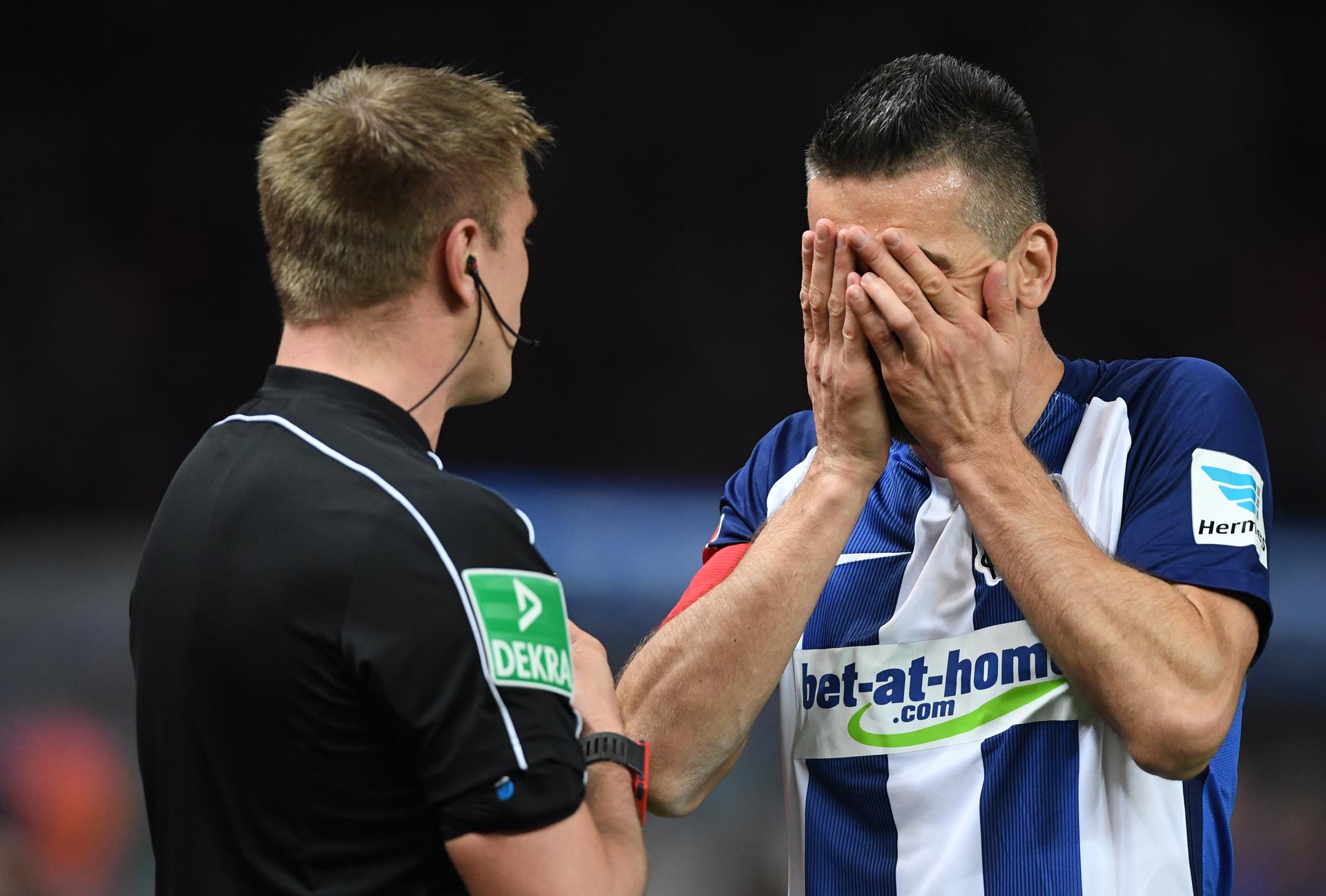 Berlins Mannschaftskapitän Vedad Ibisevic (r) hält sich nach dem Platzverweis für Mittelstädt die Hände vors Gesicht.