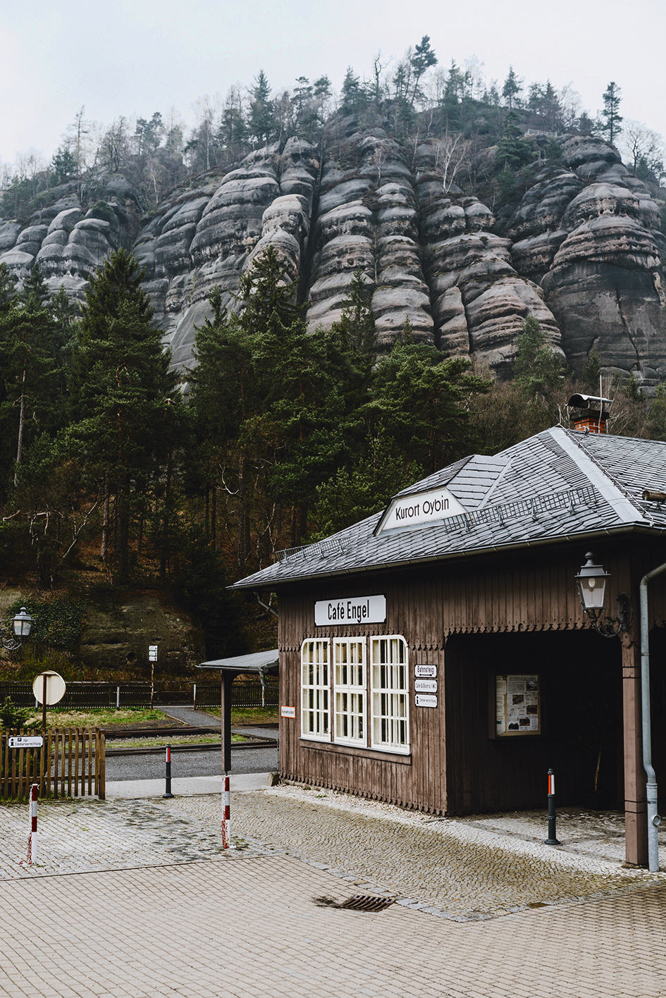 Das alte Café Engel am Schmalspurbahnhof von Oybin, dahinter ein Sandsteinplateau des Zittauer Gebirges.