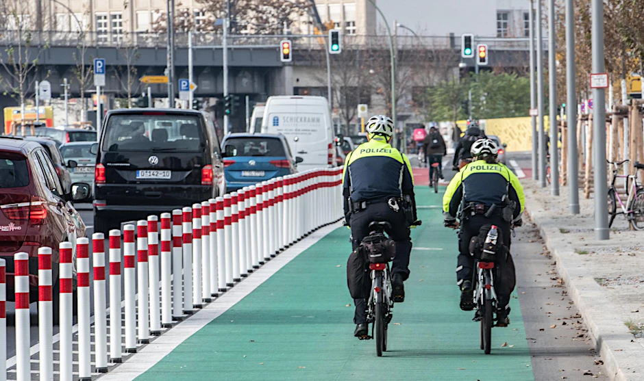 Eine Fahrrad-Streife der Polizei fährt auf den ersten geschützten Radweg an der Holzmarktstraße. Der Radweg ist mit biegsamen Pollern vom Straßenverkehr getrennt.